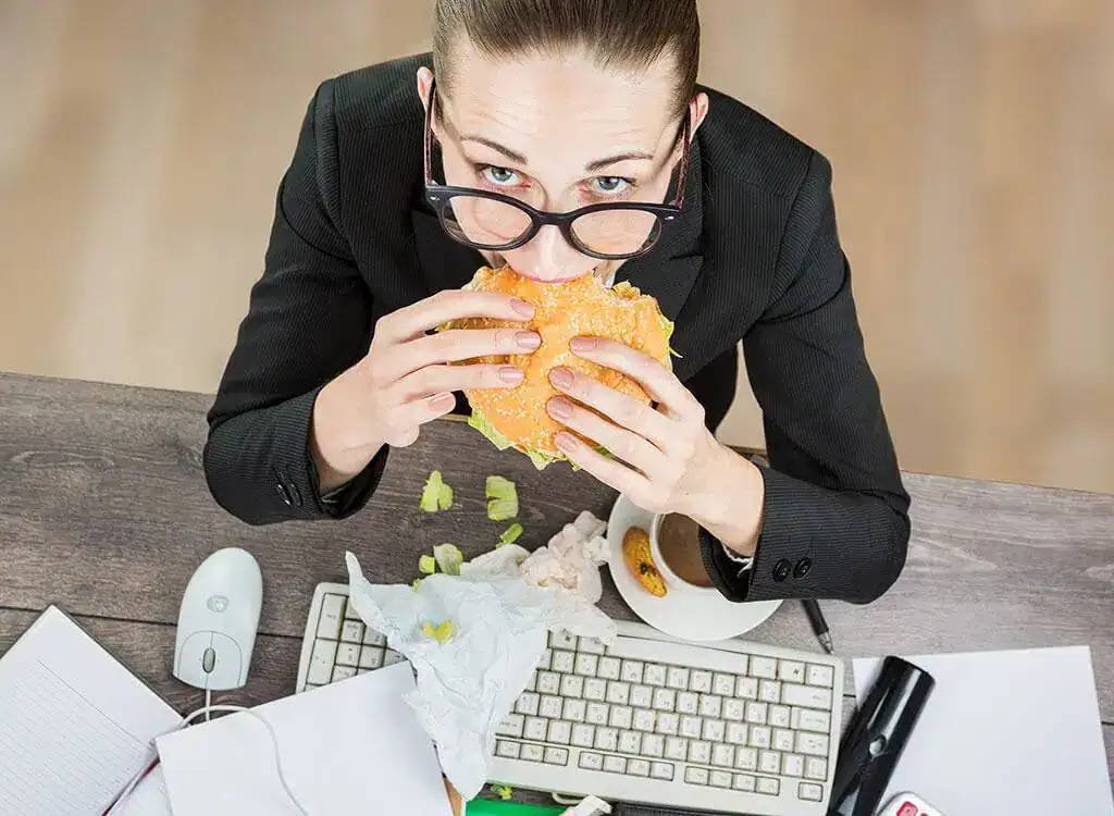 Woman Eating At Work Desk