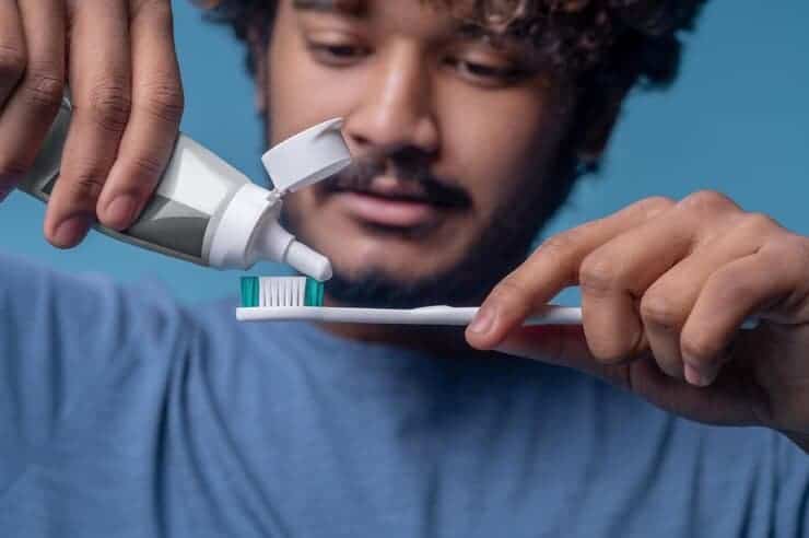 Focused Indian Male Squeezing Out Toothpaste From Open Plastic Tube His Toothbrush 259150 57695