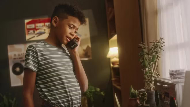 Young Boy Calling Parent Using Old Corded Phone At Home In 90s