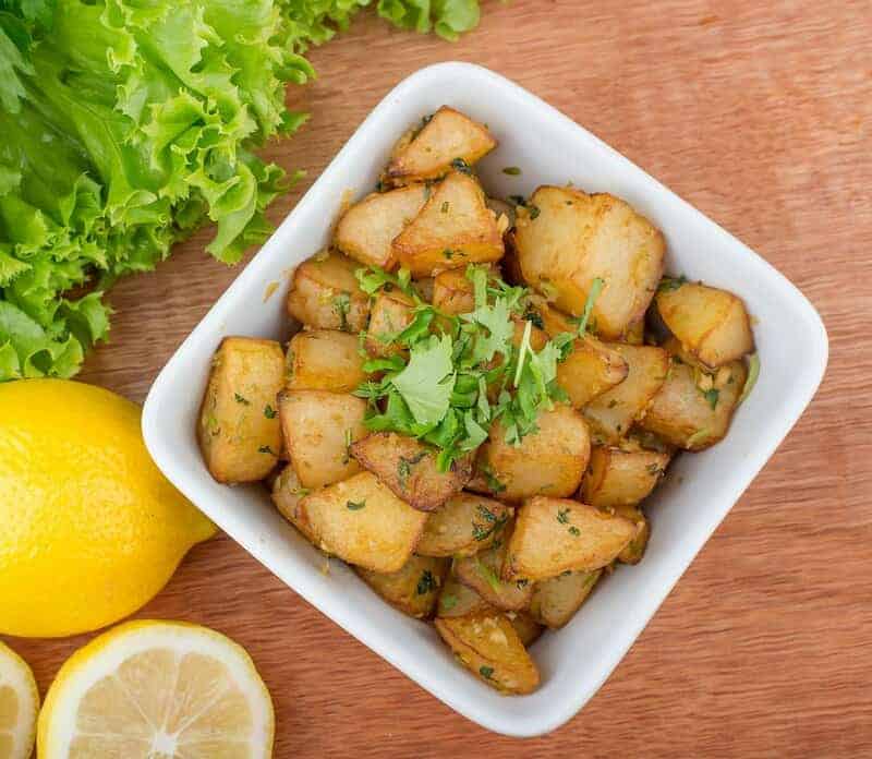 Spicy Lebanese batata harra served with lemon and lettuce.
