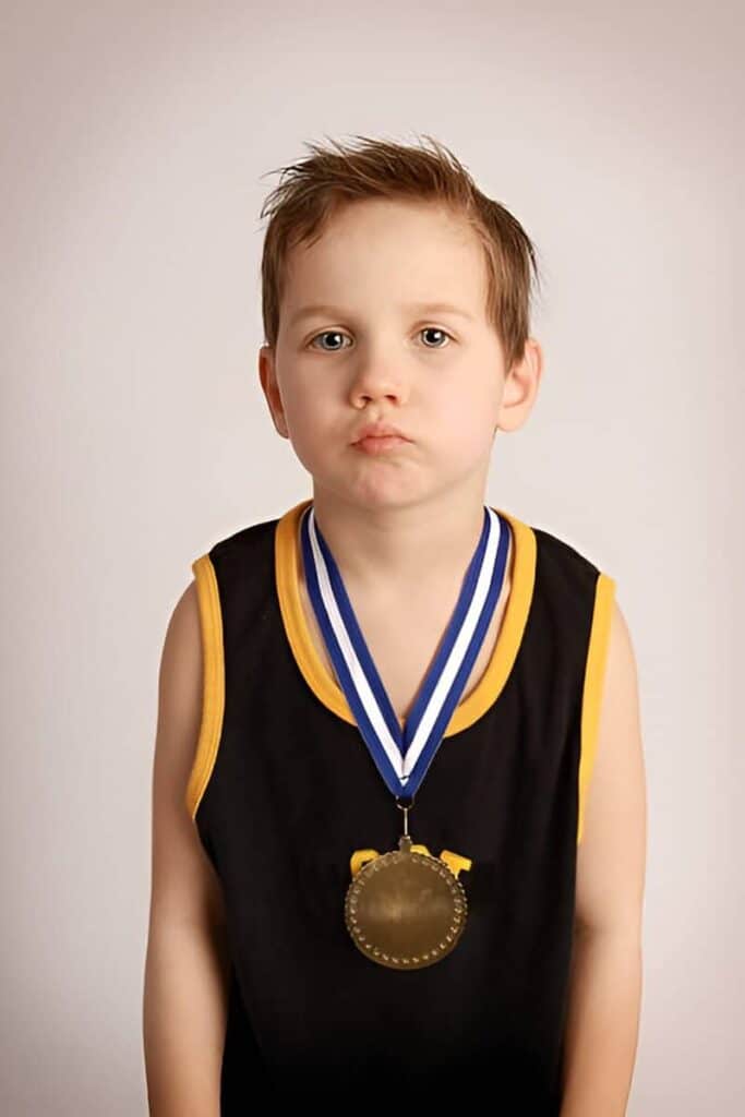 Child sits unnoticed beside scattered awards